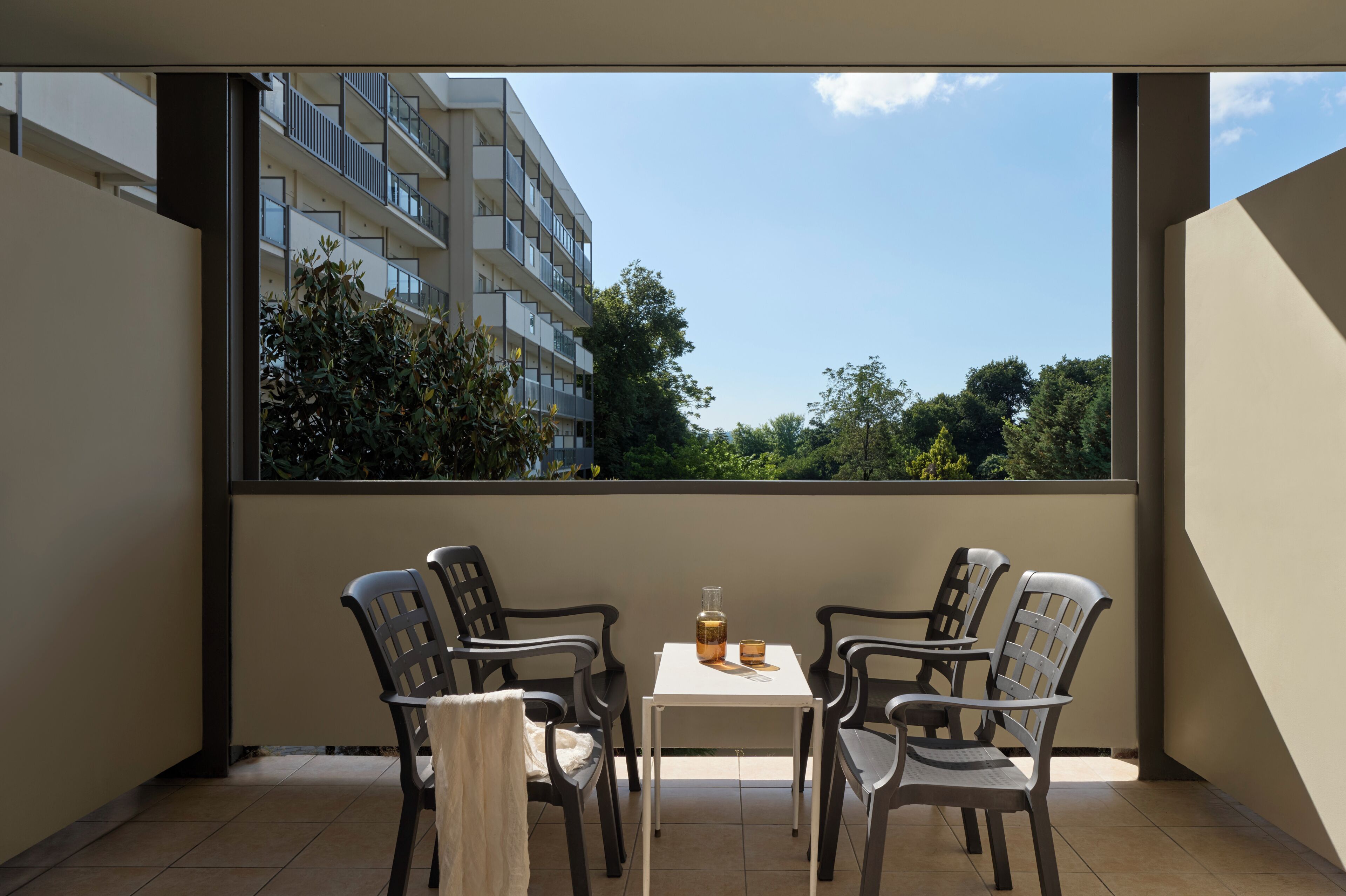 A balcony with a table and chairs, a bottle, and a glass.