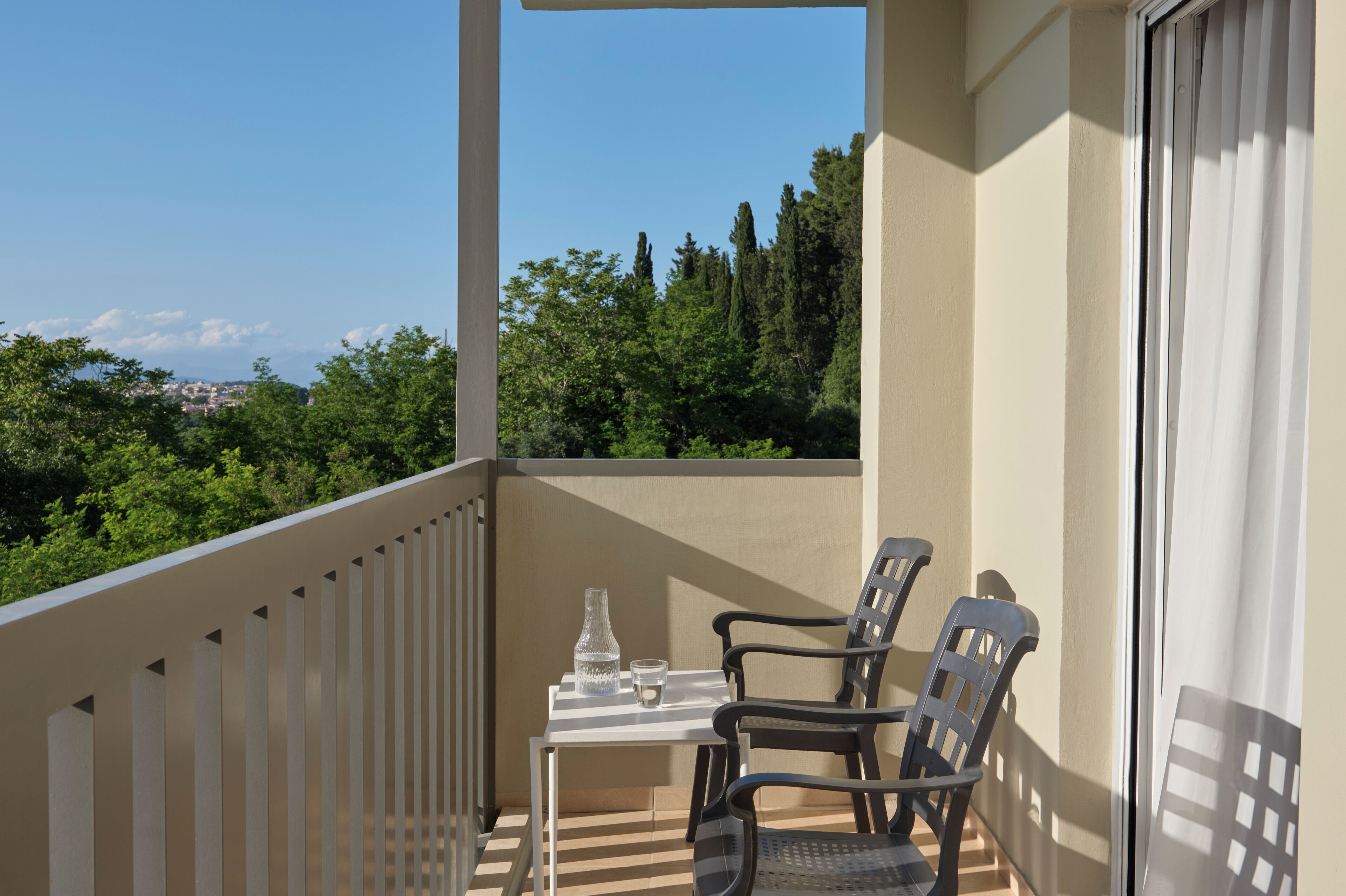 A balcony with a table and chairs, a vase, and a glass of water.