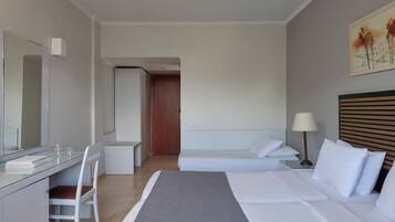 A hotel room with a bed, a desk, a chair, a bedside table, a lamp, and a painting on the wall.