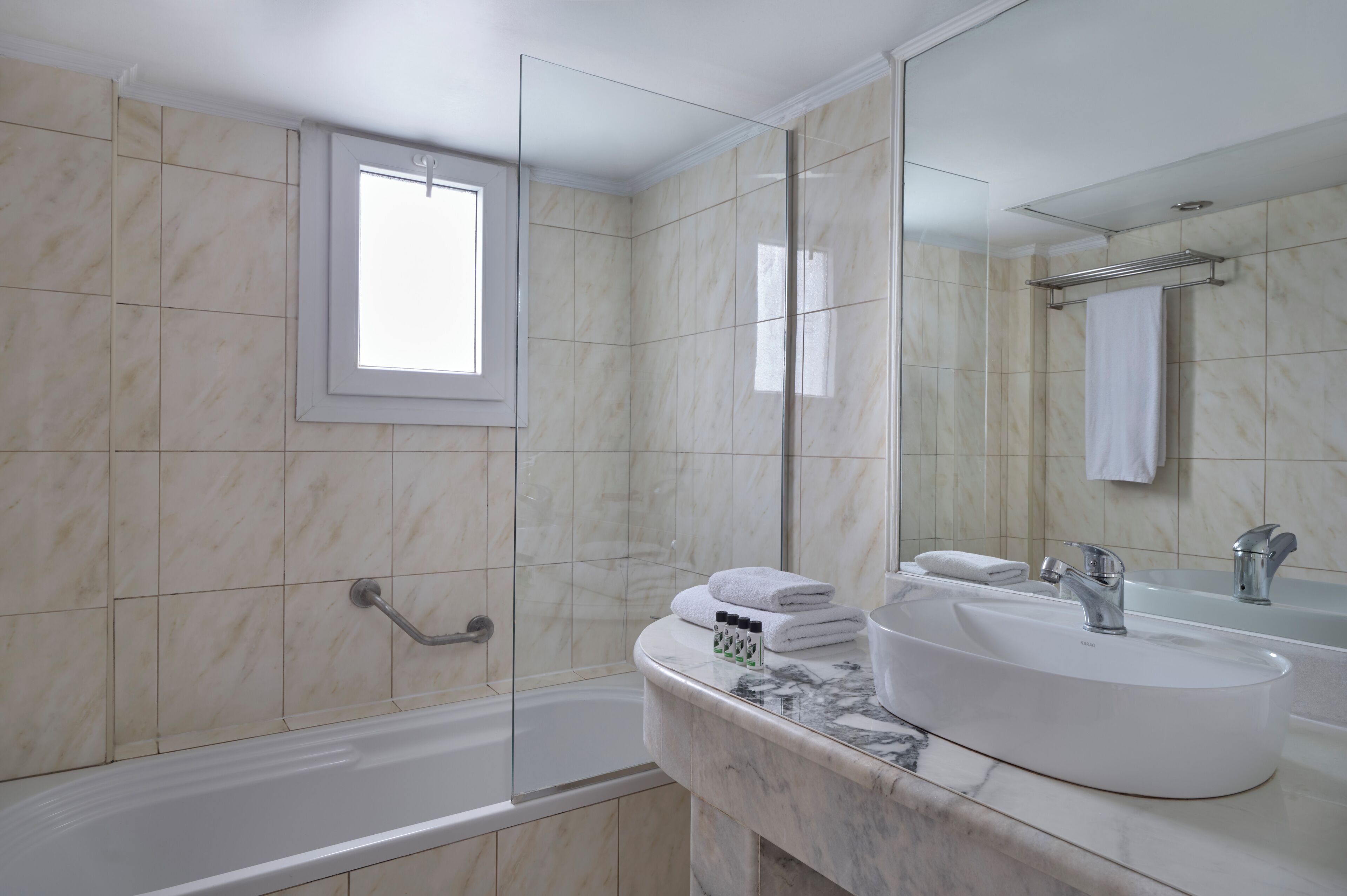 A modern bathroom with a bathtub, a large mirror, and a marble countertop.