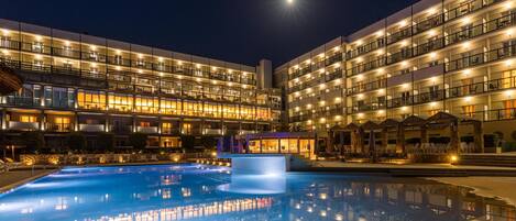 A hotel with multiple balconies, a swimming pool, and outdoor seating areas.