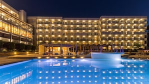 A hotel with a large swimming pool, multiple balconies, and a well-lit exterior. - Ariti Grand Hotel Corfu (Corfu)