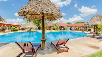 Relax by the resort pool surrounded by lounge chairs and shaded areas.