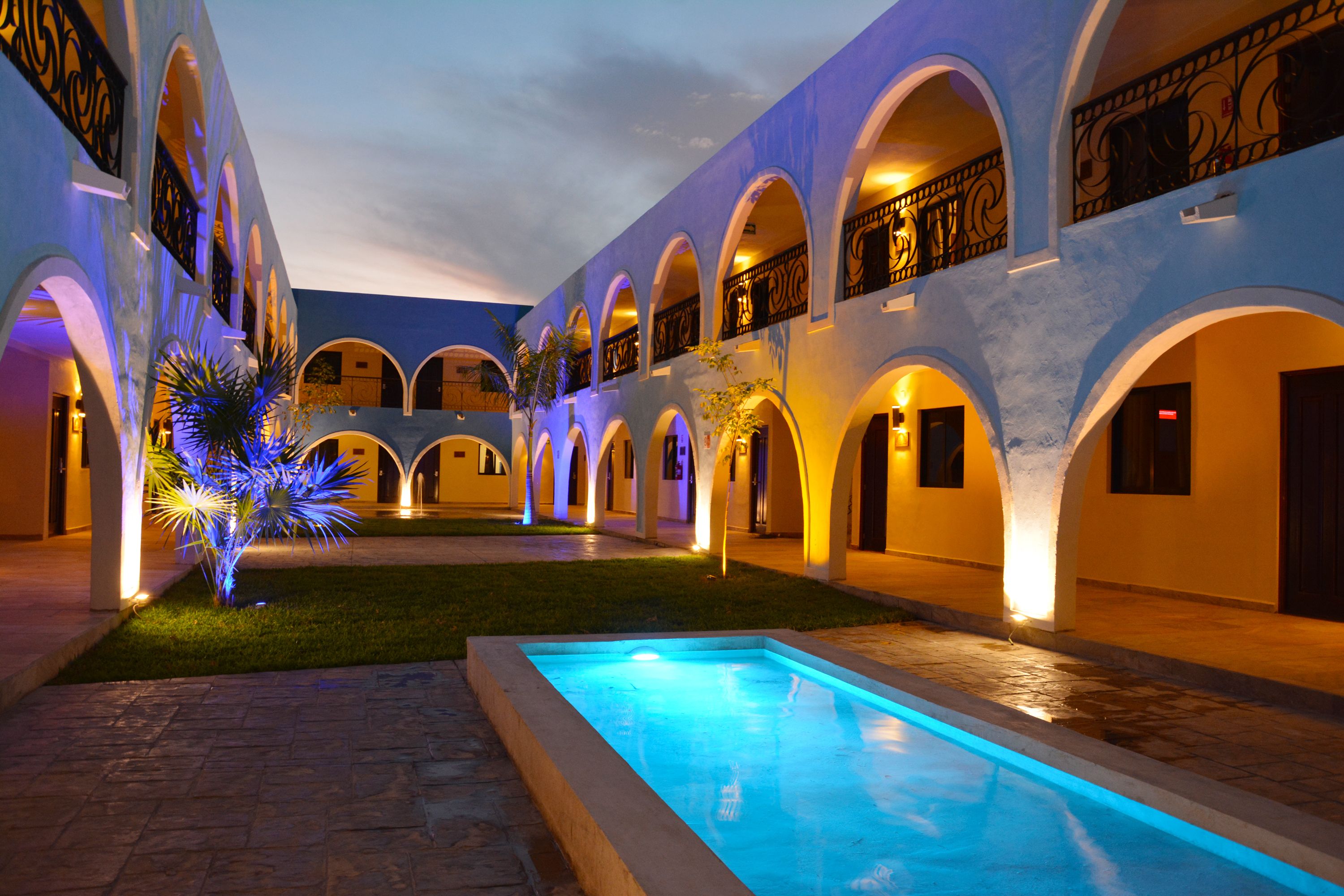 A courtyard with a swimming pool, arched walkways, and a palm tree.