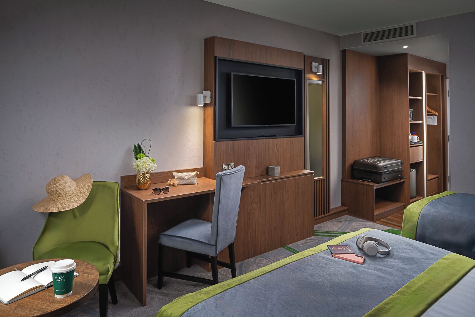 Habitación de hotel con escritorio, silla, televisor, armario y cama.