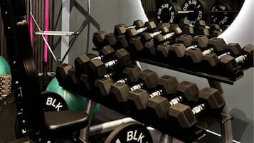 Un gimnasio con una prensa de banca, mancuernas y una jaula para sentadillas.