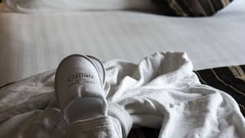 A hotel bed with a white blanket and a white bathrobe with "Carlton Hotel Dublin Airport" text.