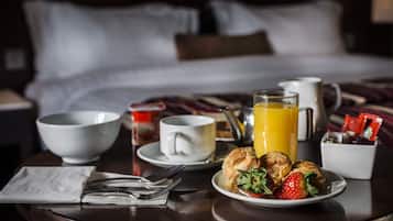 A breakfast setting with a plate of pastries, strawberries, and a glass of orange juice on a wooden table.