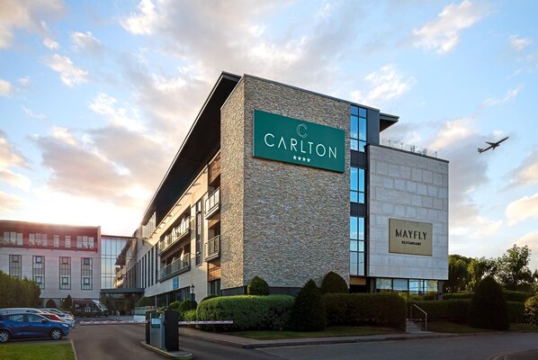Un edificio moderno con un letrero que dice 'Carlton' y un letrero que anuncia el restaurante 'Mayfly'.