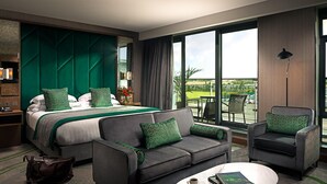 Habitación de hotel con una cama grande, dos sofás, una mesa de centro y vistas al exterior.