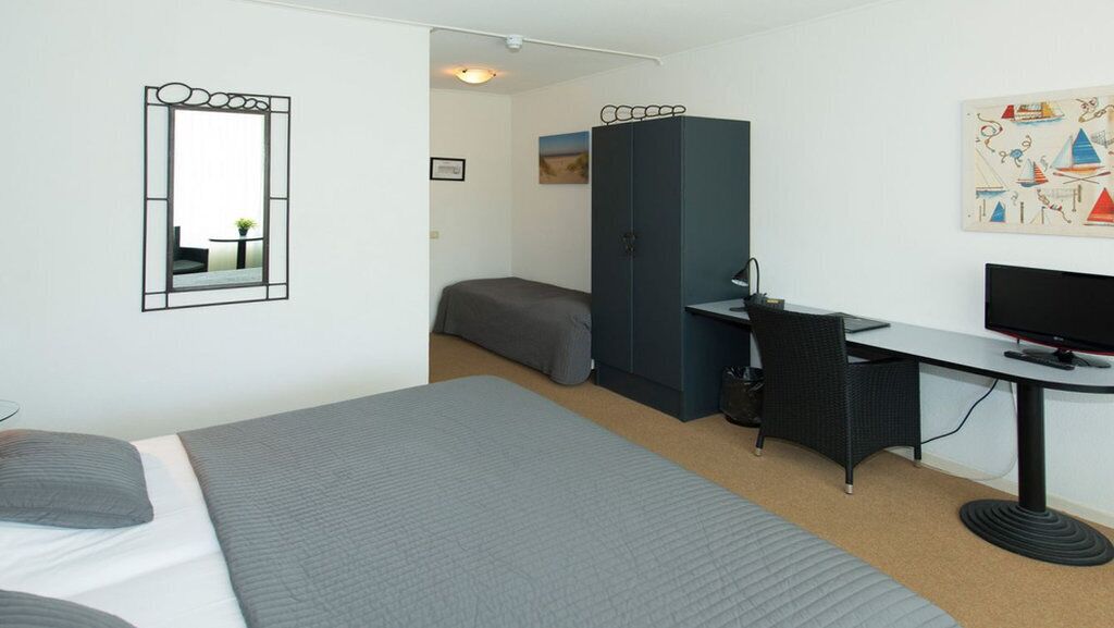 Une chambre à coucher comprenant un lit, un bureau, une chaise, une armoire et un téléviseur.