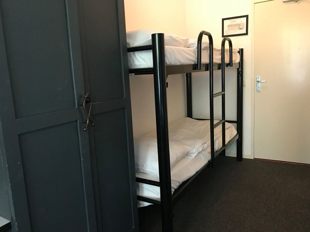 Habitación con literas, una puerta, un cuadro en la pared y suelo alfombrado.