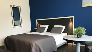 Una habitación de hotel con una cama, una mesa redonda, una silla y una planta en maceta.