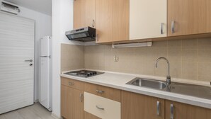 A kitchen with wooden cabinets, a stainless steel sink, and a built-in range hood. - Apartment House Volta (Porec)
