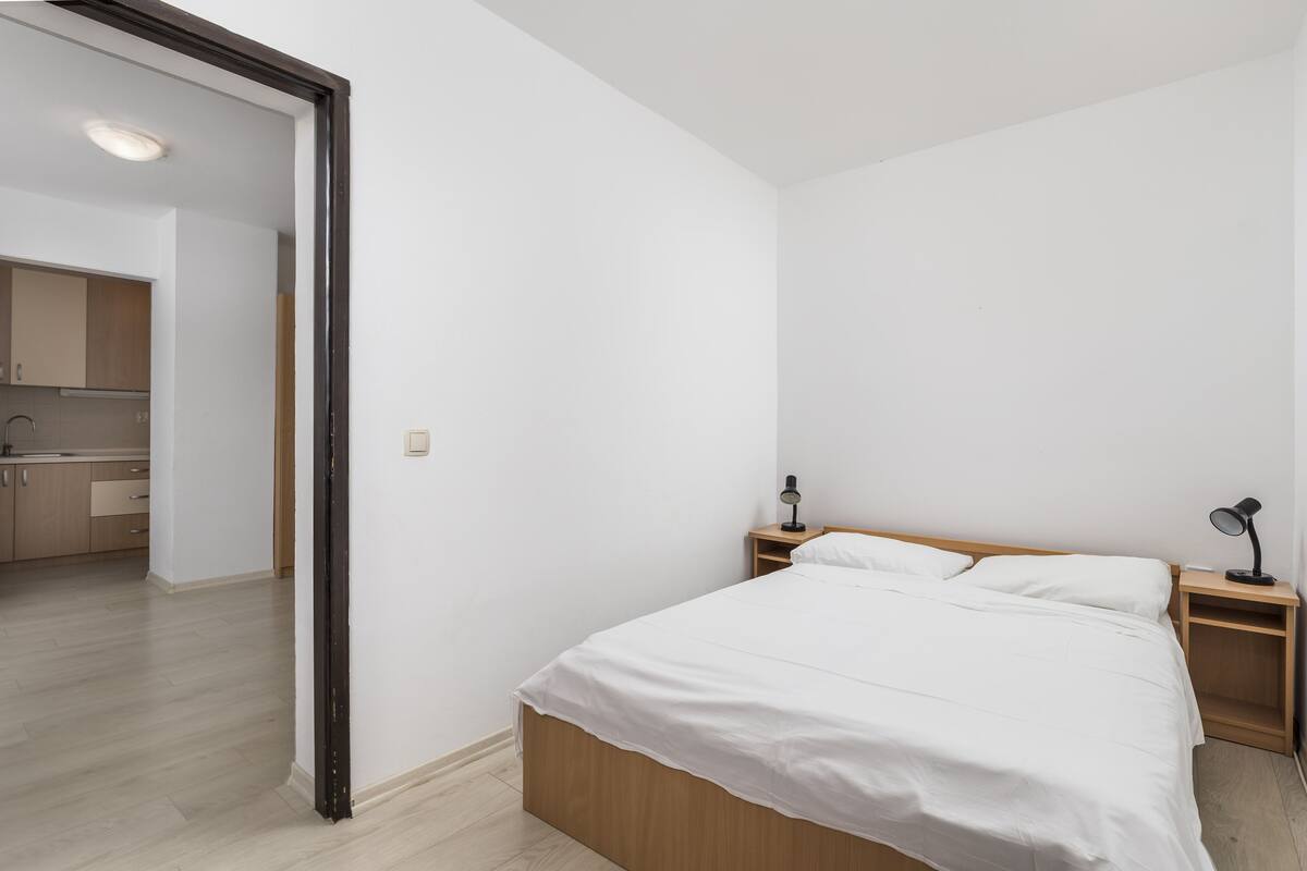 Un dormitorio con cama, mesitas de noche y vistas a una zona de cocina.
