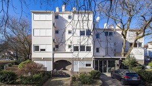 A multi-story residential building with a stone pathway leading to the entrance, a parked car, and a clear blue sky. - Apartment House Volta (Porec)