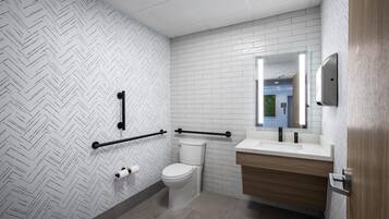 A modern bathroom with a white herringbone patterned wall, a white toilet, a wooden vanity with a mirror, and a black grab bar.