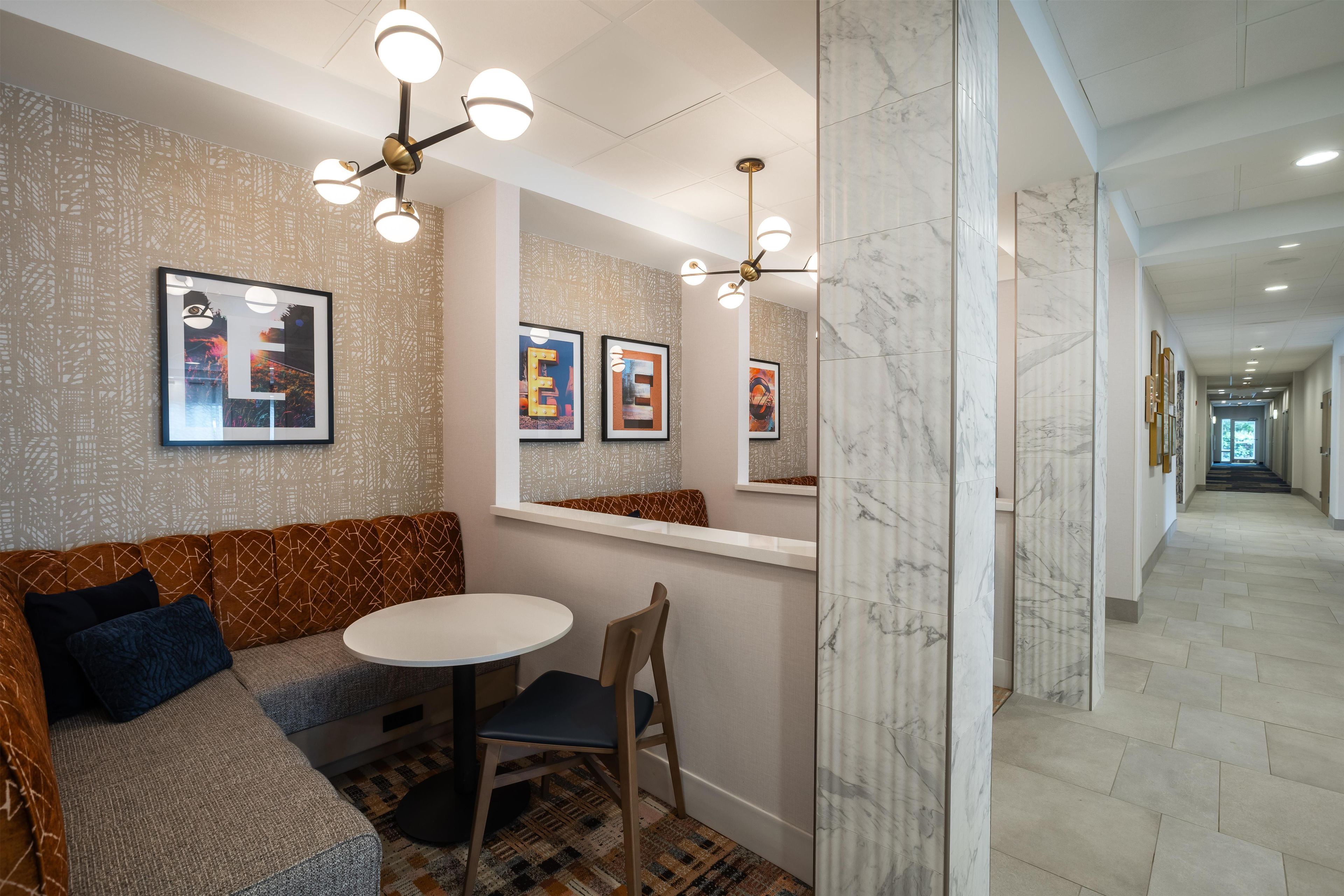 A modern interior with a seating area, a round table, and a hallway with marble flooring.