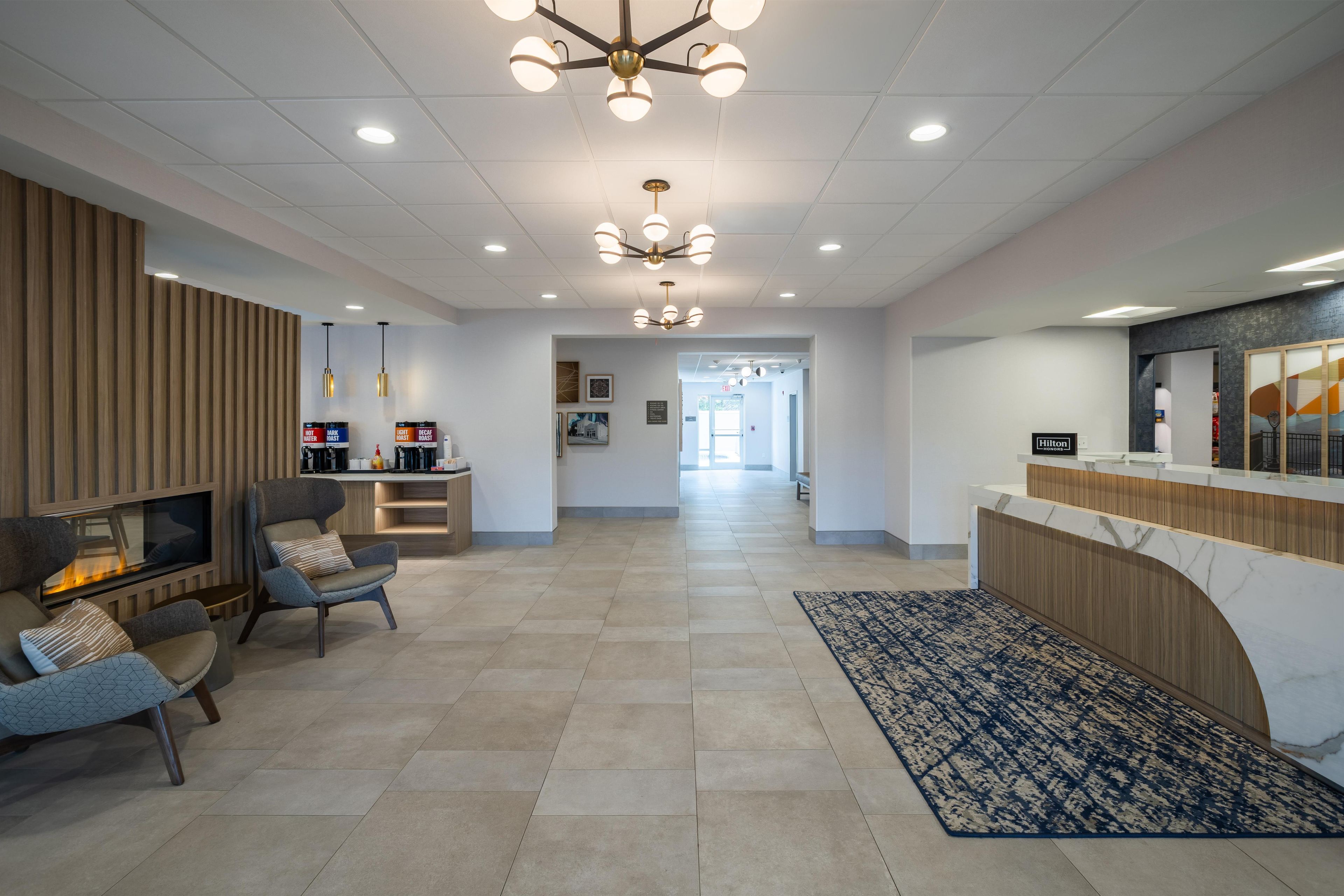 A hotel lobby with a reception desk, seating area, and a fireplace.