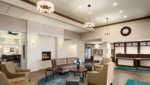 Un hall de hotel con chimenea, sofás y una mesa de recepción.