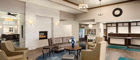 A hotel lobby with a fireplace, sofas, and a reception desk.