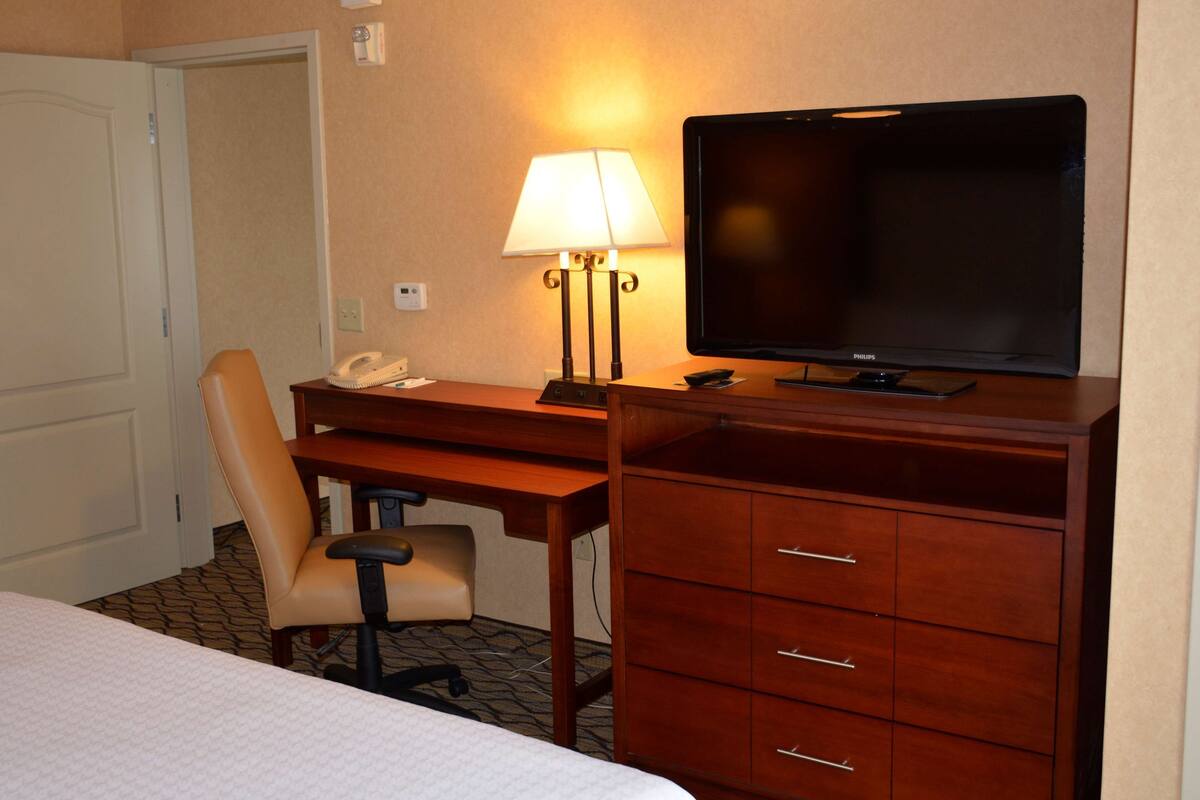 Une chambre d’hôtel comprenant un lit, un bureau avec une lampe, une chaise, un téléviseur et un téléphone.