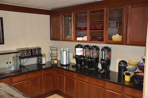 A kitchen with wooden cabinets, a black countertop, and various appliances including coffee makers and a toaster.