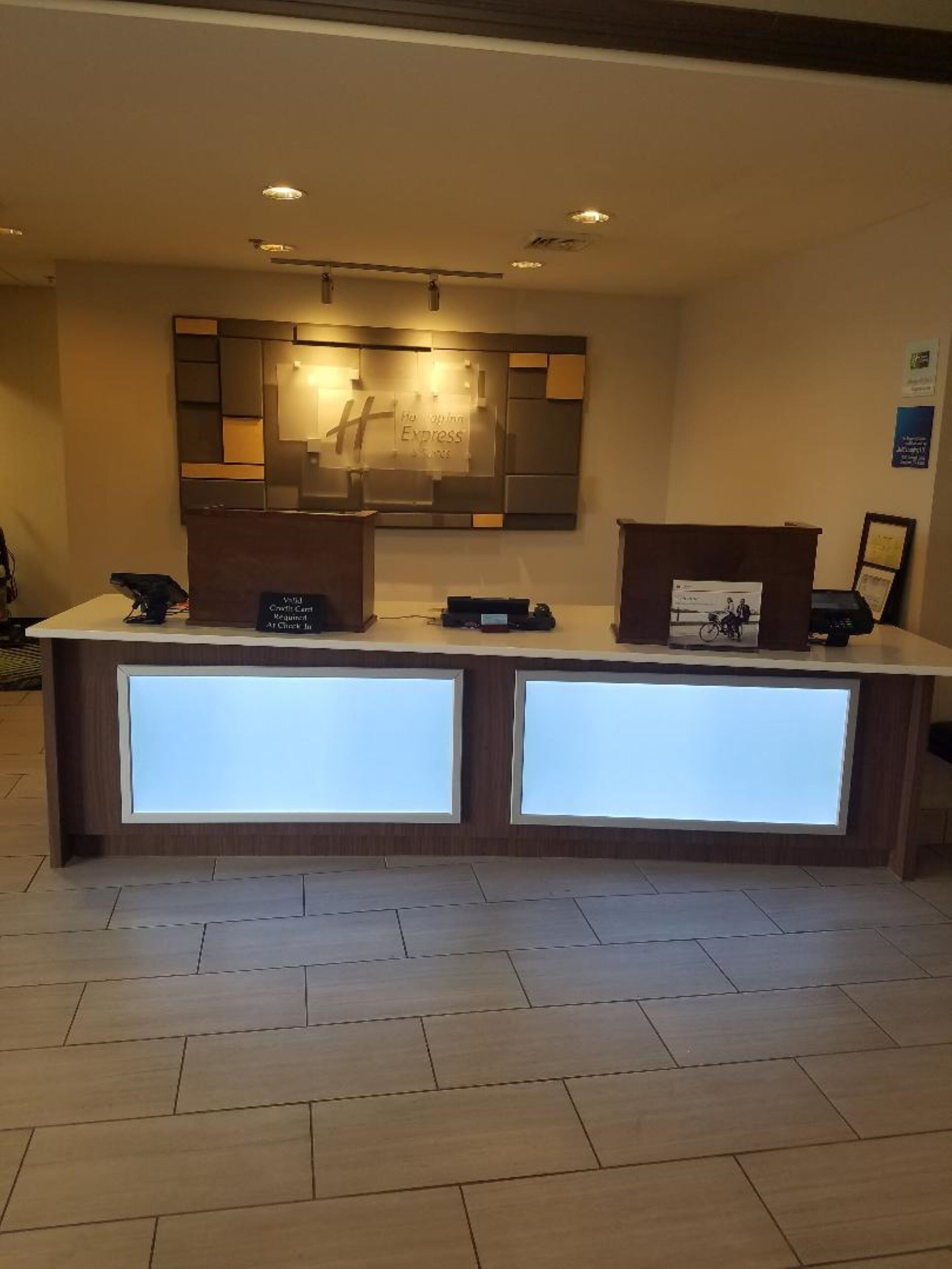 Una recepción con un diseño moderno, una pantalla digital y un cuadro en el mostrador.
