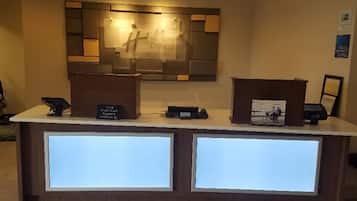 Una recepción con un diseño moderno, una pantalla digital y un cuadro en el mostrador.