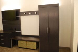 A modern room with a dark wooden wardrobe, a bench, and a flat-screen TV mounted on the wall. - Holiday Inn Express Hotel and Suites Kingsport by IHG (Kingsport)