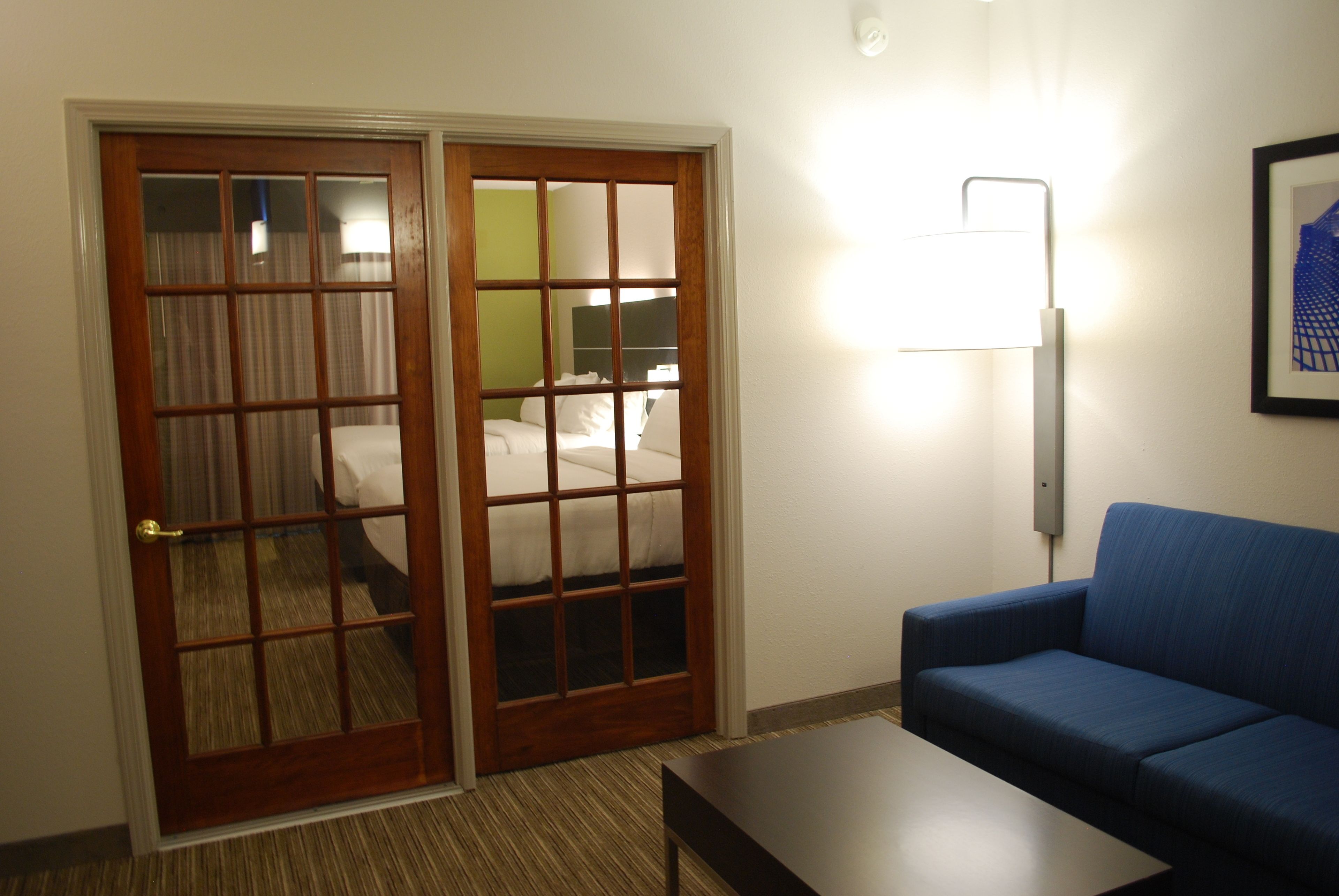 Ein Hotelzimmer mit Doppeltüren, einem Bett, einem blauen Sofa und einem Tisch.