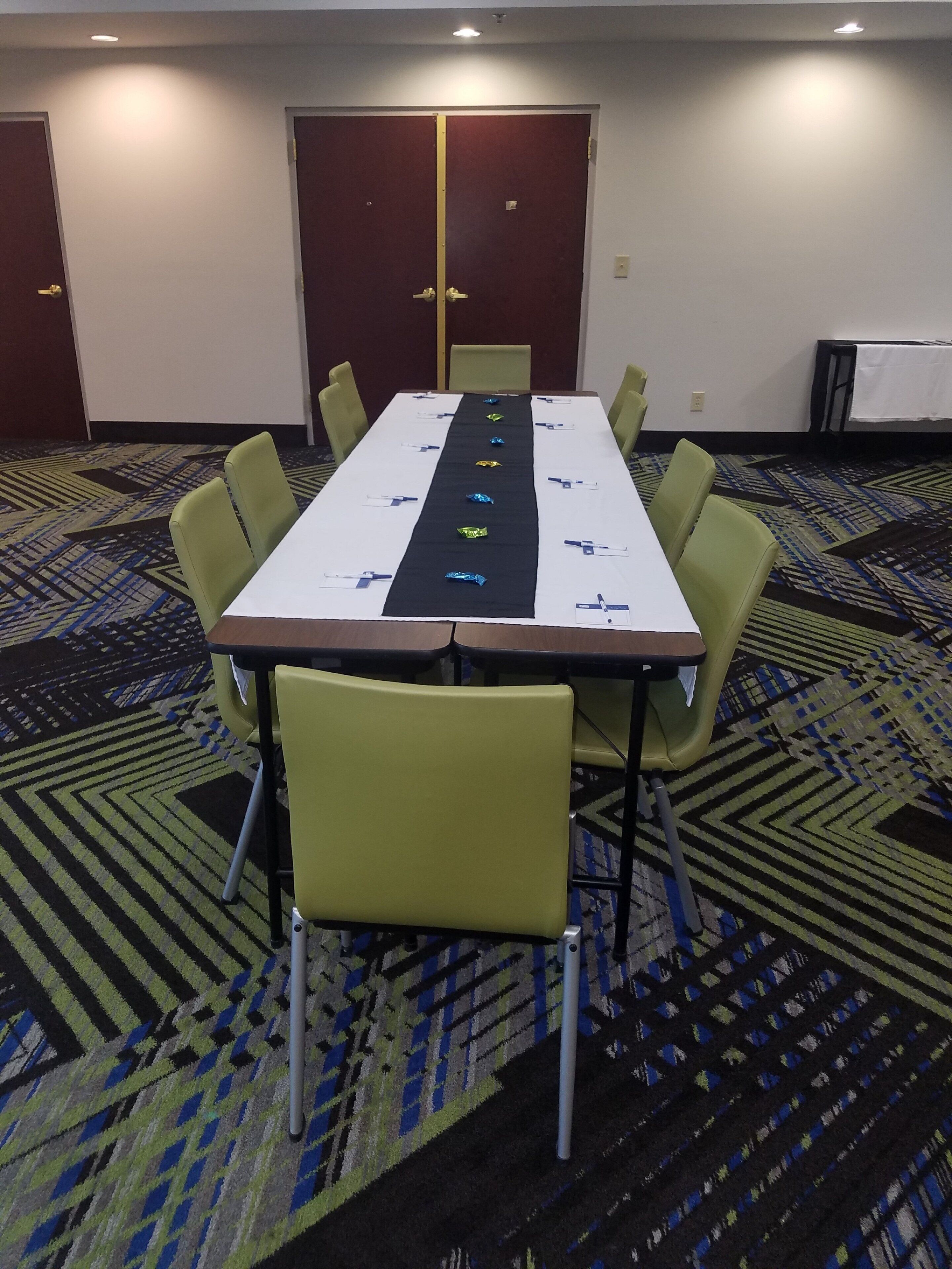 A conference room with a long table, chairs, and a carpeted floor.