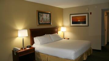 A hotel room with a large bed, two bedside lamps, a nightstand with a phone, and two framed pictures on the wall.