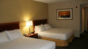 A hotel room with two beds, a nightstand with a lamp, a painting on the wall, and a carpeted floor.