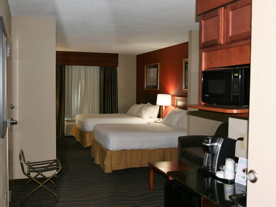 Een hotelkamer met twee bedden, een bureau, een magnetron en een koffiezetapparaat.