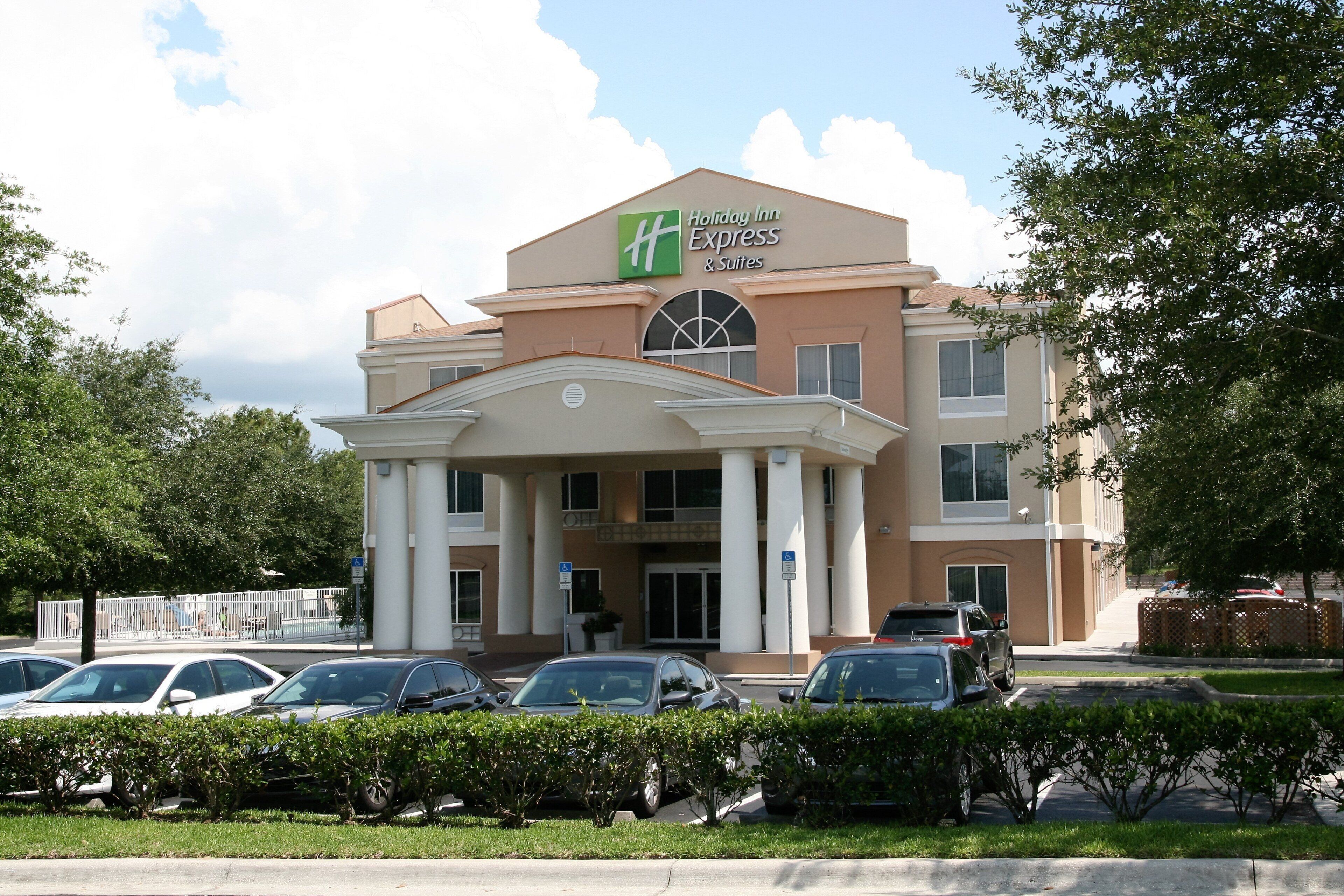 Ein Holiday Inn Express & Suites Hotel mit zentralem Eingang, Säulen und einem Parkplatz.