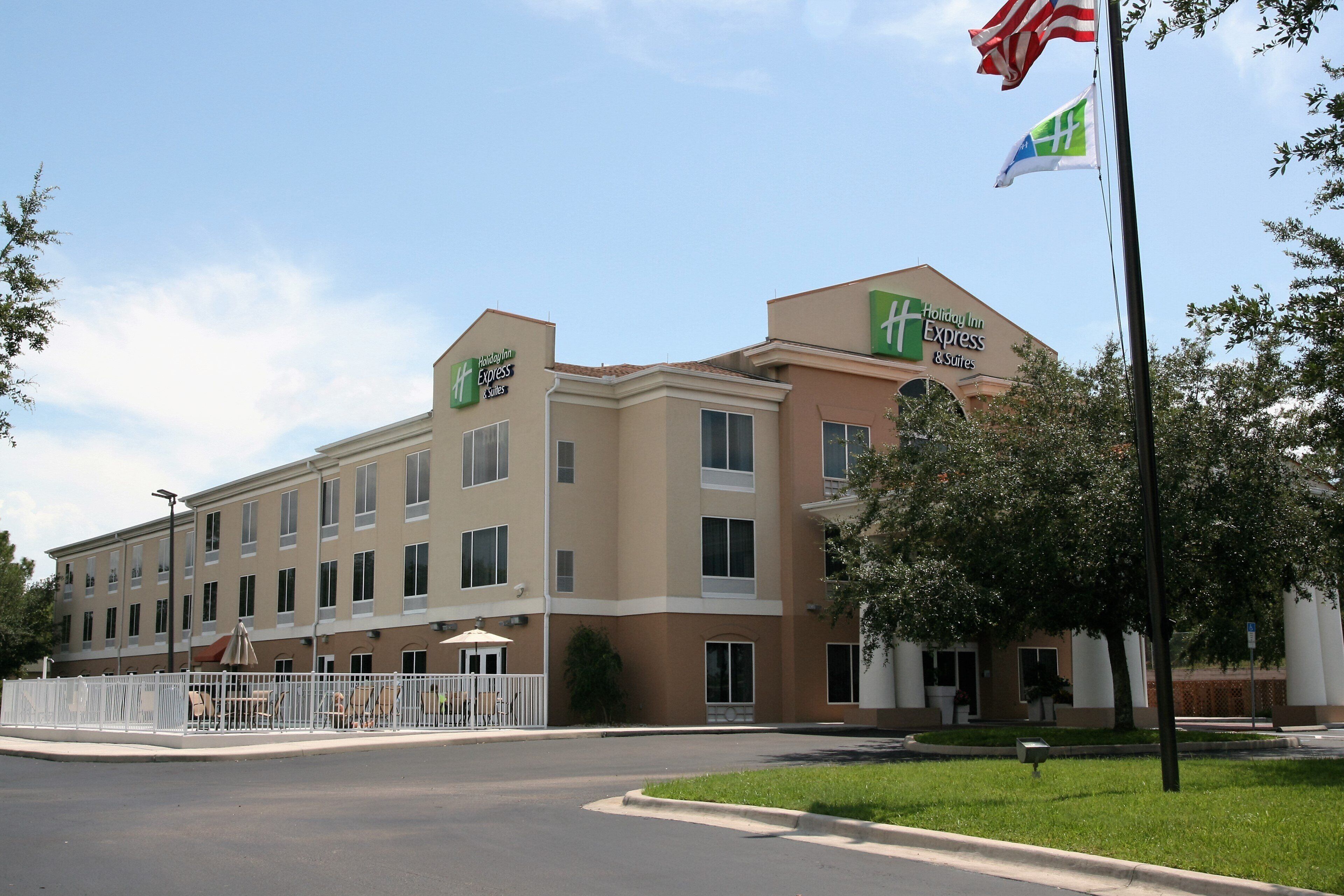 A Holiday Inn Express & Suites hotel with a flat facade, multiple windows, and a flagpole with flags.