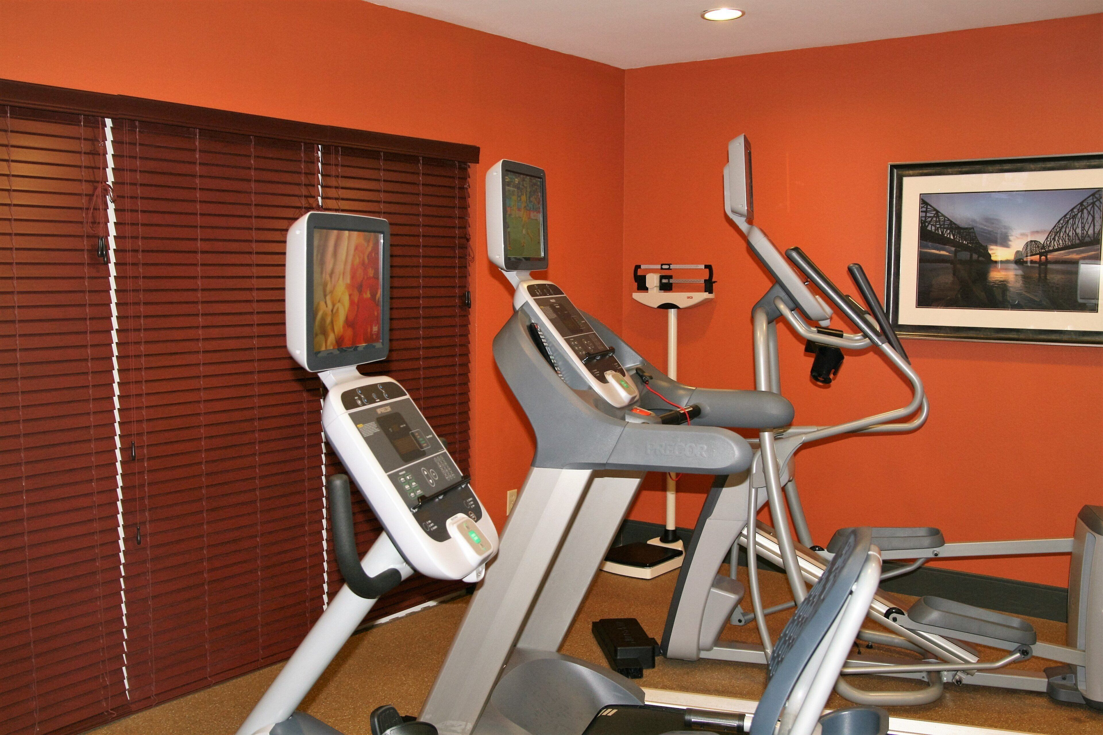 Un gimnasio con equipo de ejercicio, un televisor y un cuadro en la pared.