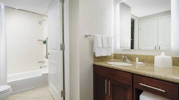 A bathroom with a bathtub, toilet, and vanity with a sink and mirror.
