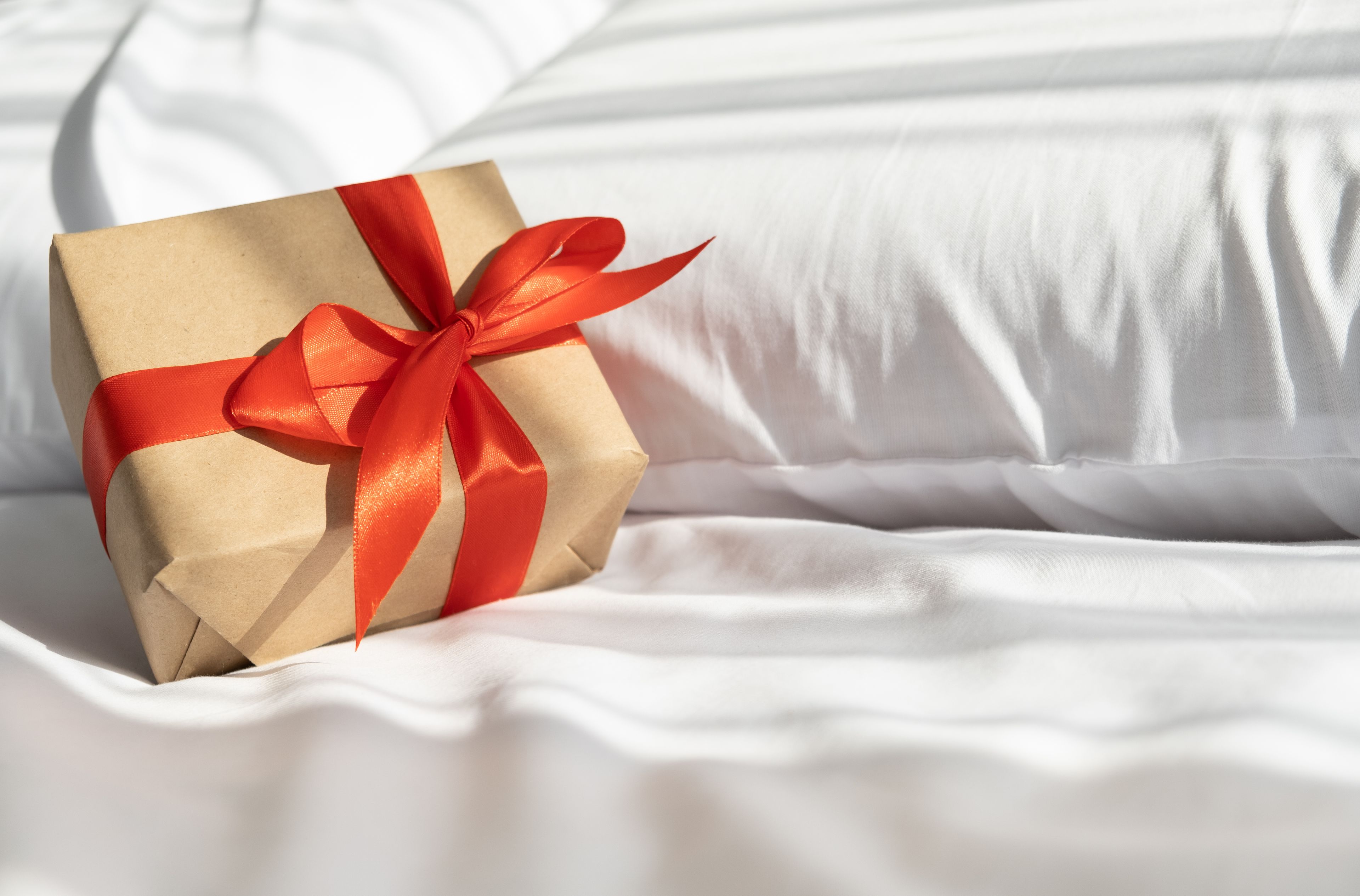 Eine Geschenkkiste mit Schleife auf einem Bett.