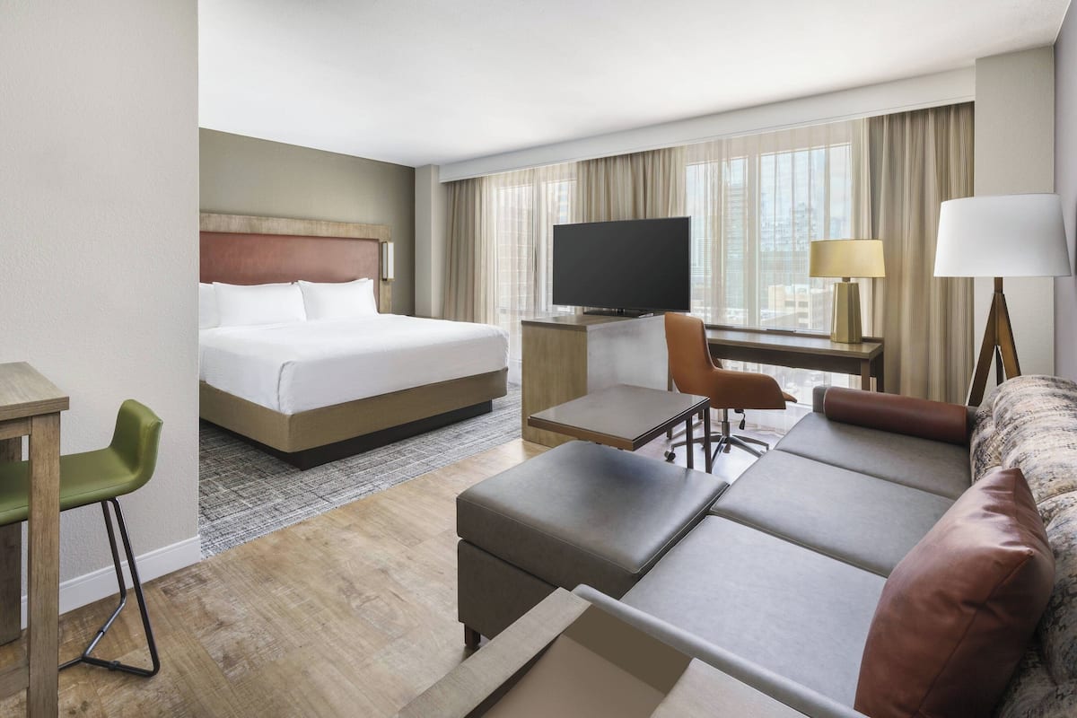 A hotel room with a bed, a desk, a television, a sofa, and a chair.