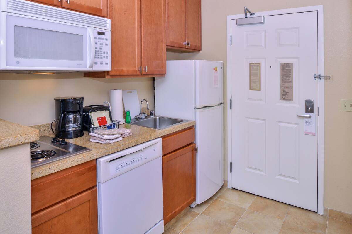 Una cocina equipada con microondas, cafetera, lavaplatos, refrigerador y lavavajillas.