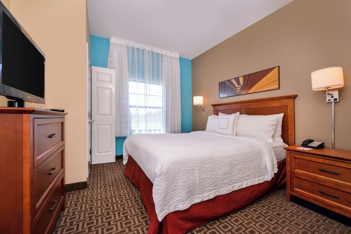 Una habitación de hotel con cama, televisión, escritorio y lámpara.