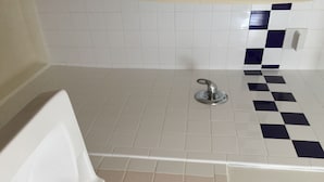 Un baño con bañera, ducha y piso de baldosas.