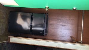 Una habitación con un armario de madera, un refrigerador negro y una pared verde.