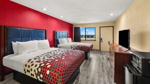 A hotel room with two beds, a TV, a minibar, and a view of the outside.