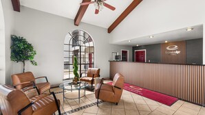 A lobby with leather chairs, a glass table, a reception desk, and a large window.