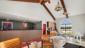 A hotel lobby with leather sofas, a reception desk, a kitchen area, and large windows offering a view.