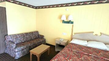 Una habitación de hotel con una cama, un sofá, una mesita de noche y una lámpara.