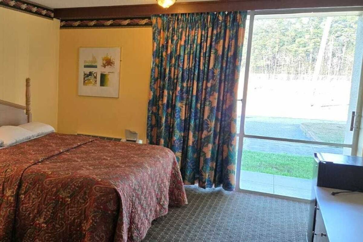 Habitación de hotel con cama, lámparas de noche, escritorio y vistas al exterior.